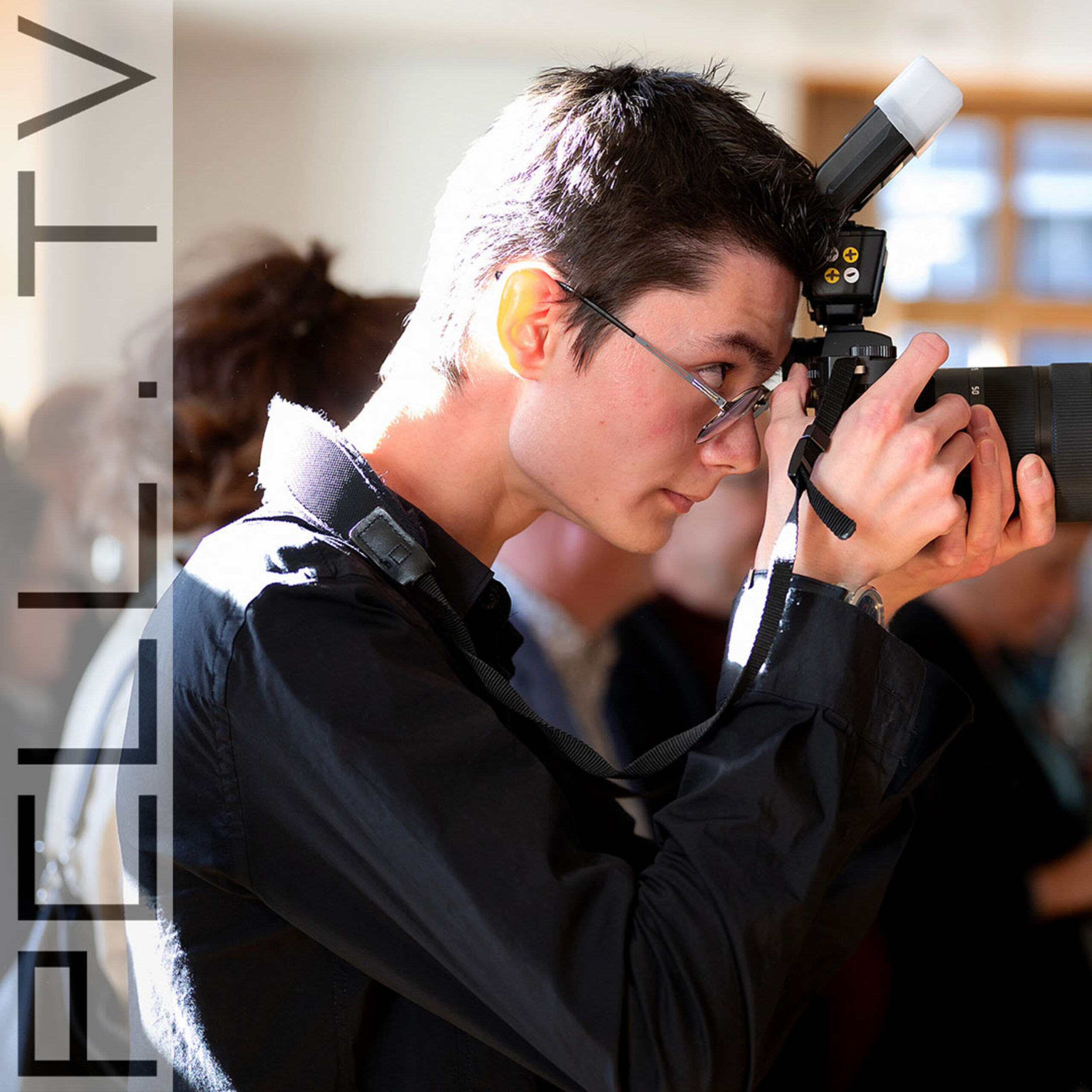 Portrait d'un jeune photographe en début de carrière, appareil en main, illustrant le fait de débuter une carrière de photographe